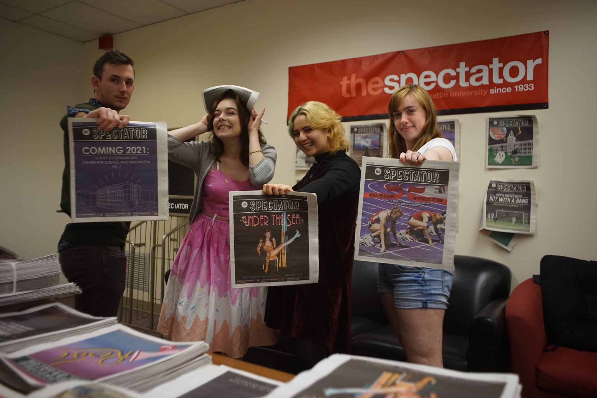 A photo of the four Spectator designers posing with issues of the paper